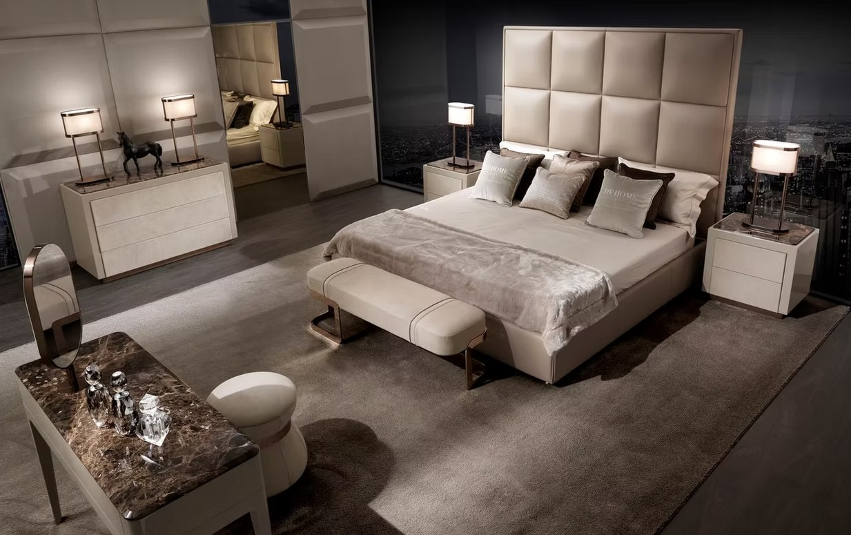 Luxurious bedroom with a padded headboard, king bed, two nightstands, and a marble-topped vanity desk.